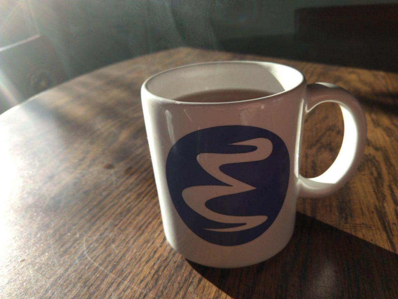 An emacs mug filled with hot tea.