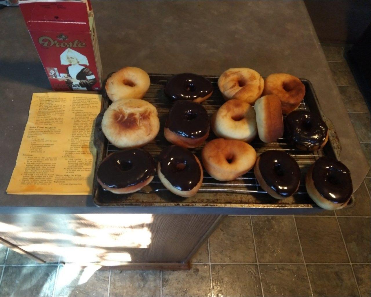 Donuts on a cooling rack, some are glazed already.
