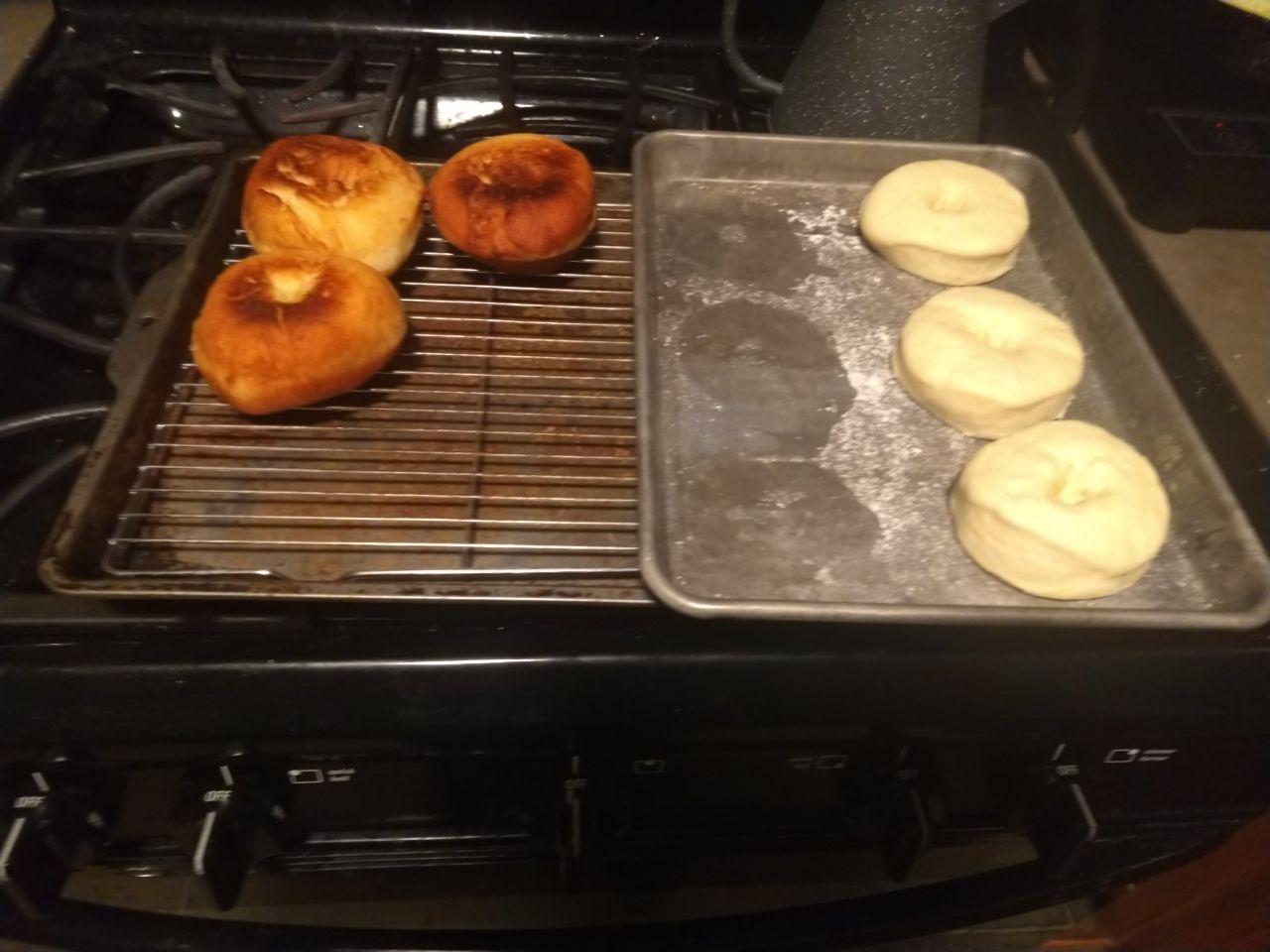 Fried donuts on a cooling rack next to raised dough.