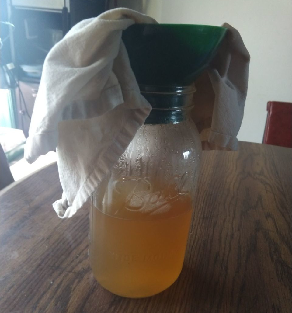 Straining ginger beer through cheesecloth.