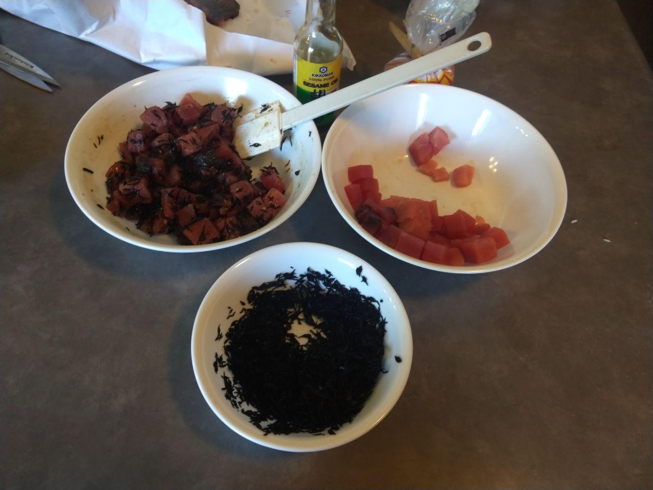 Bowl of poke being prepared with seaweed, kukui nuts, sesame oil, and salt.