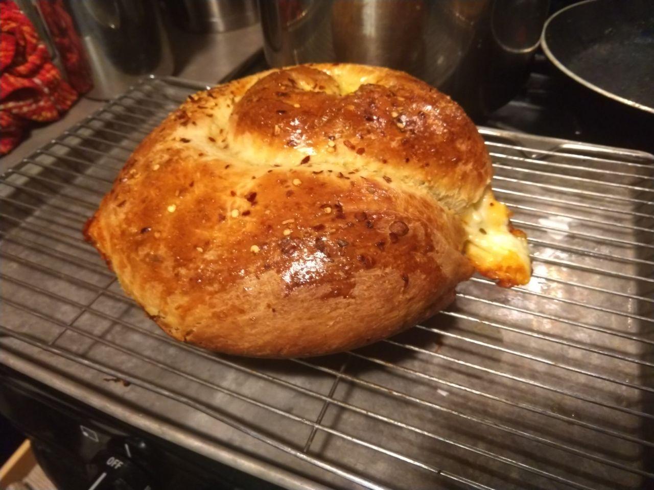 Loaf of spicy cheese bread on cooling rack.